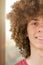 Split in half cropped portrait of a young curly European man with long curly hair and a dreamy smile close-up against the window.