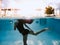 Split shot of girl leaping underwater and the poolside cabanas above the water