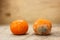 Spoiled moldy rotten tangerine next to a ripe and beautiful tangerine wooden table