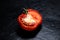 Spoiled, rotten, flabby tomato on black background