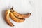 Spoiled tainted bananas on grey background. Ugly food trendy photo. Food waste, food garbage