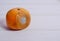 Spoiled tangerine with mold on a white wooden background