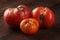 Spoiled three tomatoes on a dark wooden background.