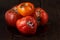 Spoiled three tomatoes on a dark wooden background.