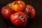 Spoiled three tomatoes on a dark wooden background.