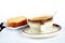 Sponge cake with the cup of coffee, spoon, knife and fork on white ceramic plate