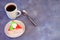 Sponge triangular cake in red glaze, a small silver spoon and a white ceramic mug with hot coffee