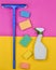 Sponges, window mop, sprinkler cleanser on a pink yellow background. Objects for home cleanliness. Products for cleaning