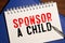 Sponsor A Child text written on a notebook with pencils