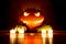 Spooky carved halloween pumpkin with candles and small pumpkins