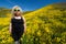 Spooky, creepy blonde woman wearing green alien sunglasses in a field of goldfield wildflowers in Carrizo Plain National Monument