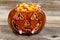 Spooky fanged pumpkin filled with candy corn on rustic wood