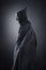 Spooky figure with hooded cape over dark background