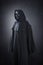 Spooky figure with hooded cape over dark background