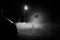 A spooky ghost of a woman in the road below a single street light in the countryside. Lit up by car headlights at night. With a
