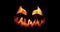 Spooky Halloween jack o` lantern with scary face carved out of a pumpkin glowing with flickering light