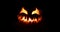 Spooky Halloween jack o lantern with scary face carved out of a pumpkin glowing with flickering light and emitting smoke