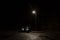 A spooky, mysterious hooded figure, standing next to a car under a street light at night
