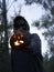 Spooky shot of a European guy holding a smoking Halloween pumpkin while wearing a facemask