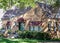 Spooky vintage cottage with awnings is decorated for Halloween with skeletons crawling on roof and huge spider web