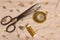Spool of Gold Thread and Scissors With Thimble on Metallic Fabric
