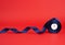 Spool of twisted dark blue silk shiny ribbon on a red background