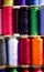 Spools of multi-colored sewing threads. White red green yellow orange blue.