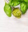 Spoon with Basil pesto and herbs leaves on white woooen background