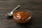 Spoon and bowl with caramel condensed milk on wooden background