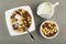 Spoon in bowl with cereal breakfasts and yogurt, pitcher with yogurt,  bowl with rings on gray table. Top view