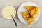 Spoon in bowl with condensed milk, folded thin russian pancakes in plate on wooden table. Top view