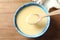 Spoon and bowl of condensed milk on table, top view. Dairy products