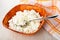 Spoon in bowl with defatted cottage cheese, napkin on wooden table