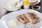 Spoon in bowl with flour, salt, condiment in bowl, pieces of pollock fillet, flour in dish on table