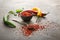 Spoon and bowl with granulated chili pepper on light background