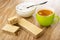 Spoon in bowl with sugar, halves of wafer, whole wafer, coffee in cup on wooden table