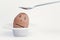 Spoon breaks sad egg on a stand in the form of human head .