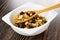 Spoon with cereal breakfast with peanut and raisin in white bowl on wooden table