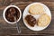 Spoon with chocolate melted cheese in jar, plate with slices of bread, sandwich on table. Top view