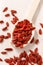 Spoon of dried goji berries, wooden background