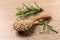 Spoon with dry rosemary and fresh twigs on wooden table, closeup