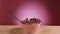 Spoon falls into a deep bowl filled with chocolate corn balls and milk. Flakes and splashes of milk fly in different