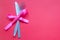 Spoon with a fork tied with a ribbon on a pink background. Cutlery