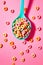 Spoon full of corn rings or cereals on pink pastel background. Ai generative
