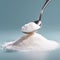 Spoon full of refined granulated sugar or stevia on top of a heap of refined sugar or stevia.