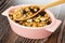 Spoon with granola in bowl with cereal breakfast with peanut and raisin on wooden table