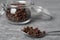 Spoon and jar with aromatic dry cloves on grey table