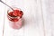 A spoon on a jar filled with superfood goji berries on white wood