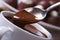 Spoon with liquid chocolate and cup closeup horizontal.