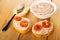 Spoon with liver pate on slice of bread, liver pate in bowl, sandwiches with liver paste and tomato on table